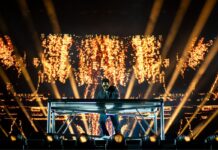 Bluesfest Day 9 review: Kaytranada ends festival on a high note with an energetic finale A DJ plays on stage in with a backdrop of golden spotlights and sparks.