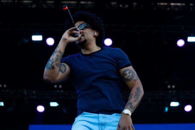 A rapper in a dark blue t-shirt performs on stage.
