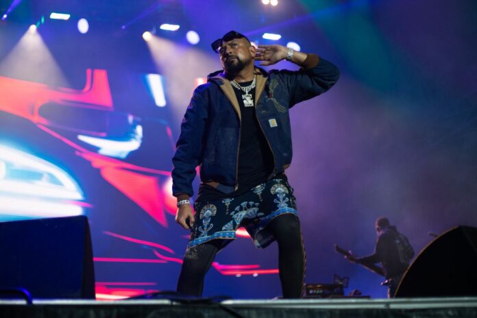 A man sings on a stage, and listens to the crowd singing back.