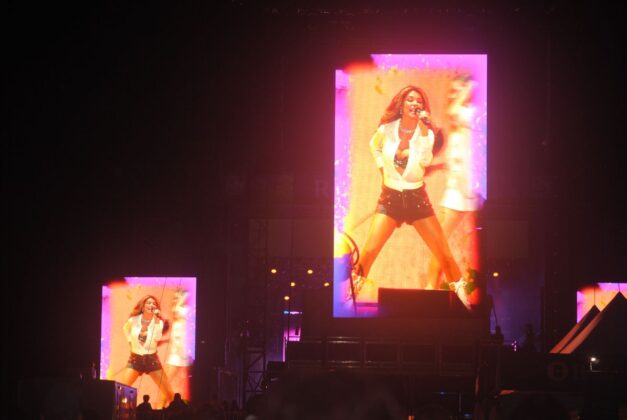 Two screens show a woman passionately singing on a stage.