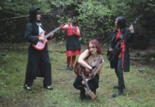 Review: ‘Forensis’ album files through the wreckage of young love Four people in red and black extravagant clothing stand with instruments in a forest clearing.