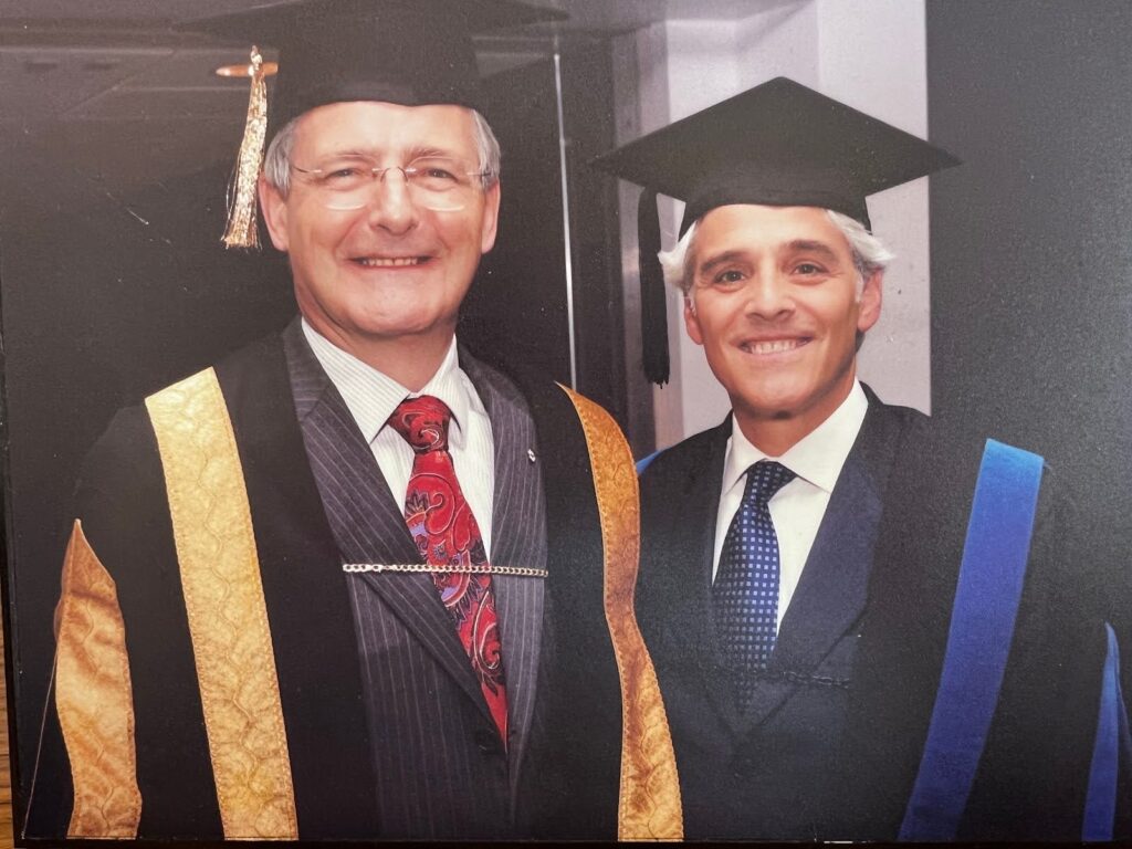 Two men standing together wearing graduation caps. 