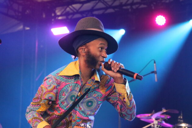 A peron in a colourful outfit sings on stage.