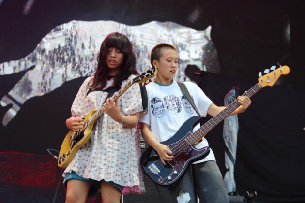 Two guitarists rock out on a stage.