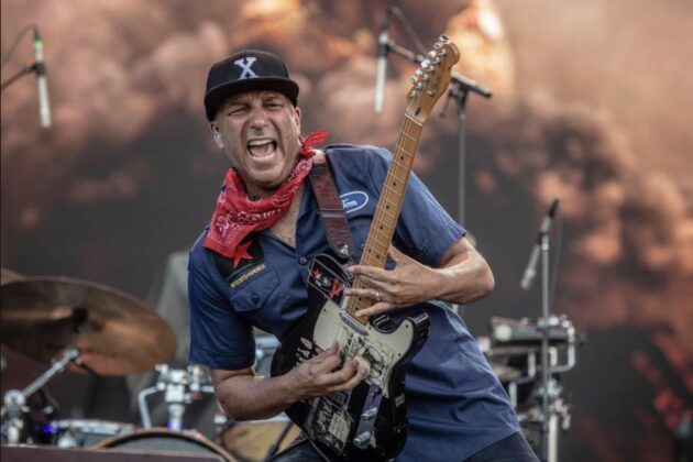 A person performs guitar passionately on stage.