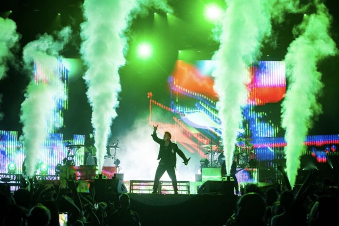 A singer performs on a stage with green smoke