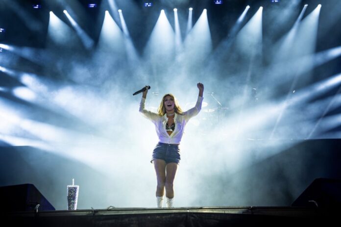 A woman with a white and black sparkly outfit performs on a stage with all spotlights turned to her.