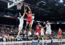 Shorthanded BlackJacks championship hopes end against Shooting Stars Basketball player wearing red reaches to the basket surrounded by players wearing white.