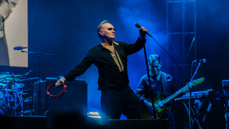 A performer with a tambourine sings on stage.