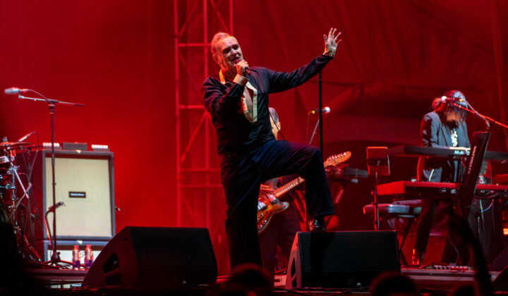 A singer performs on stage under a red spotlight.
