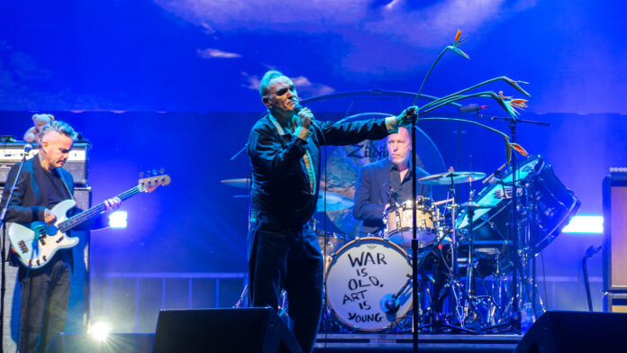 A band performs on stage under a blue spotlight.