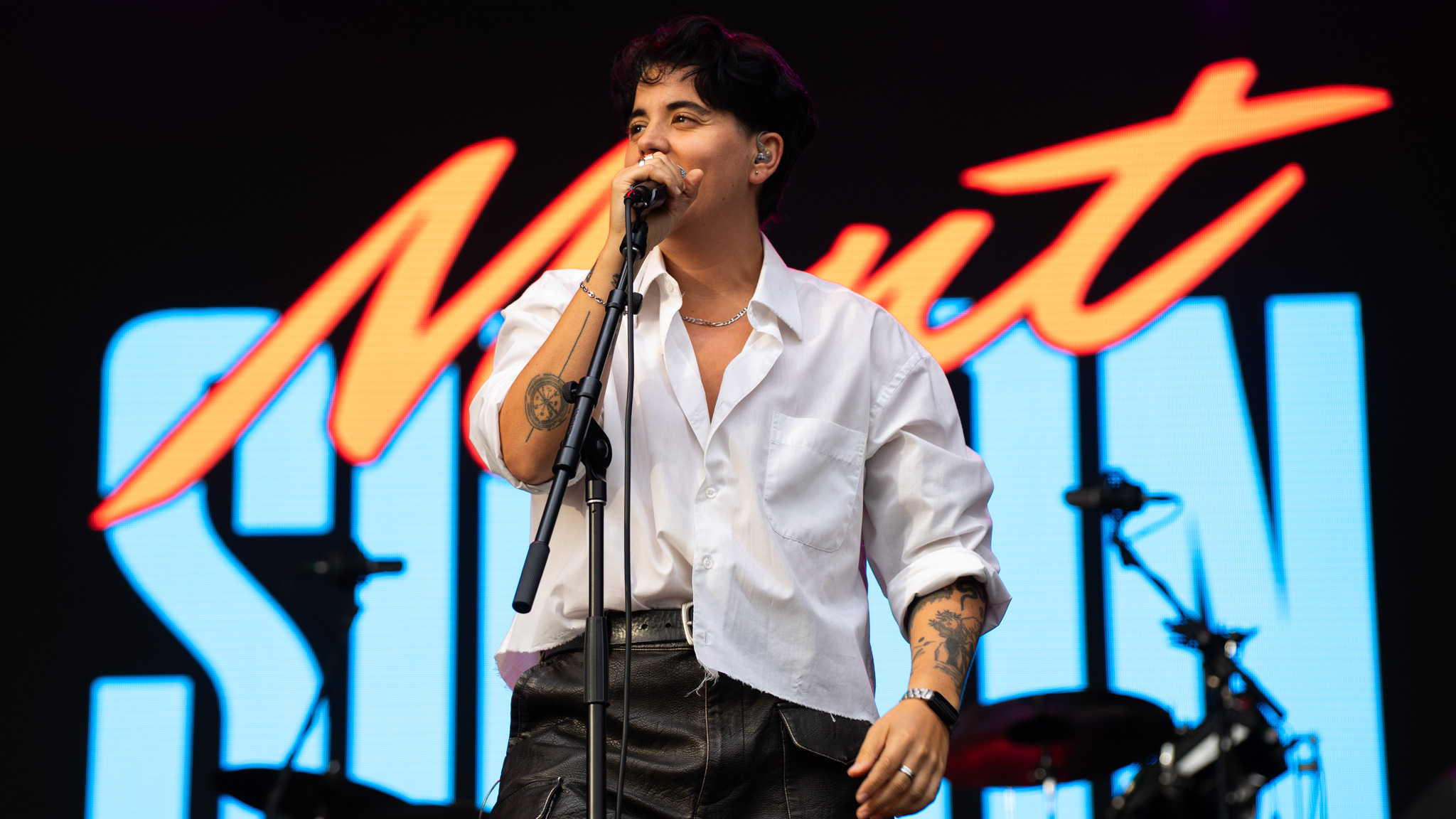 A singer in a white shirt sings on stage.