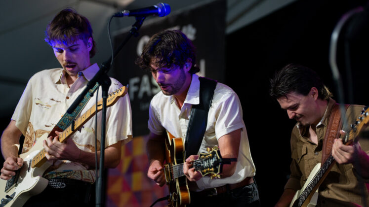 A trio band performs on stage.