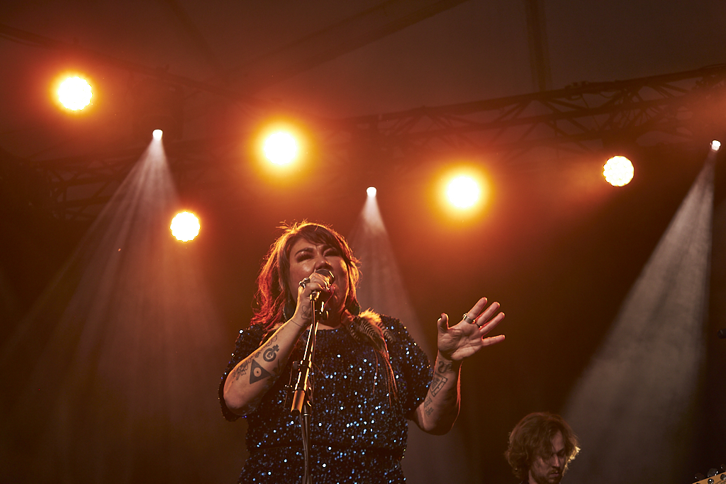 A singer sings under an orange spotlight on stage.