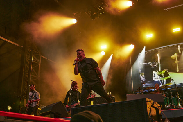 A singer performs on stage under orange lighting.