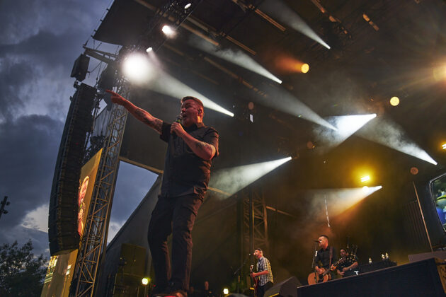 A singer performs on a stage under yellow and white lighting.