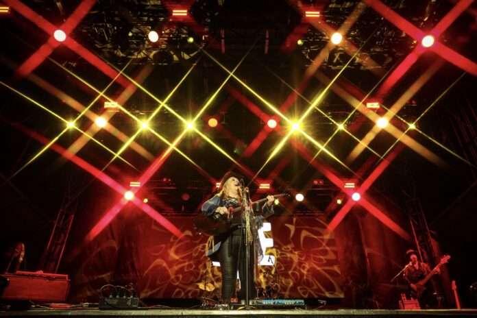 A performer sings on stage under red and yellow lighting.