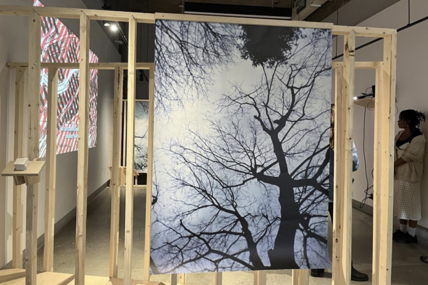 A photo of trees and sky is hung on wooden posts.