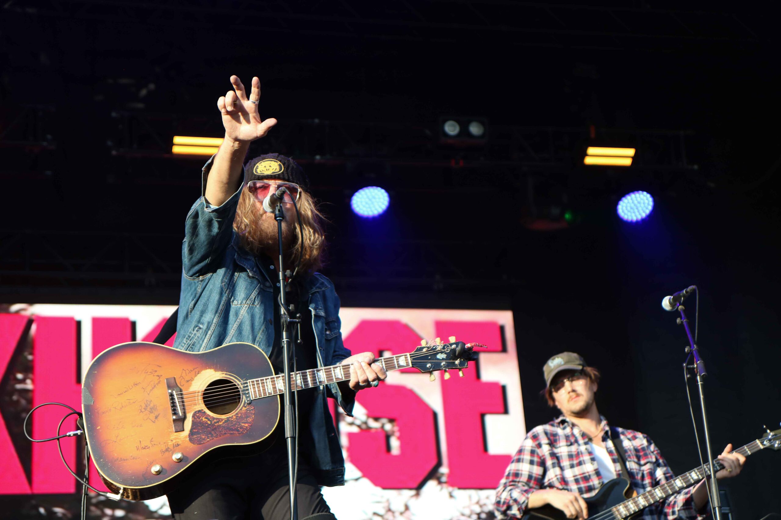 A band performs on stage, the lead singer reaches out to the crowd.