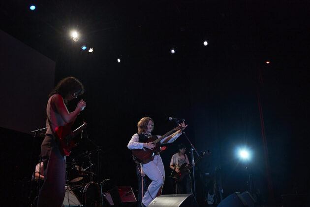 A band performs on a darkly-lit stage.