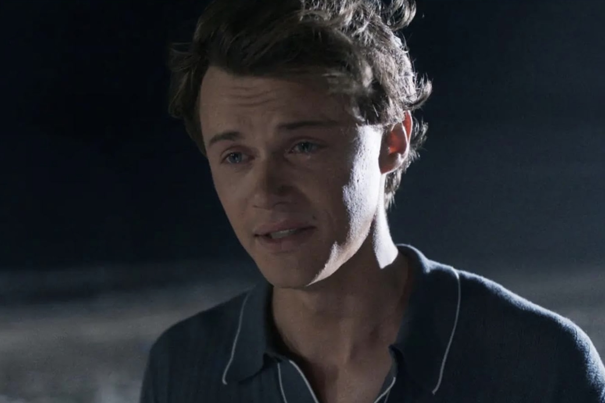 A man cries on the beach at night.