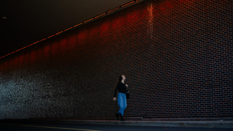 person walks in underpass where there are orange lights