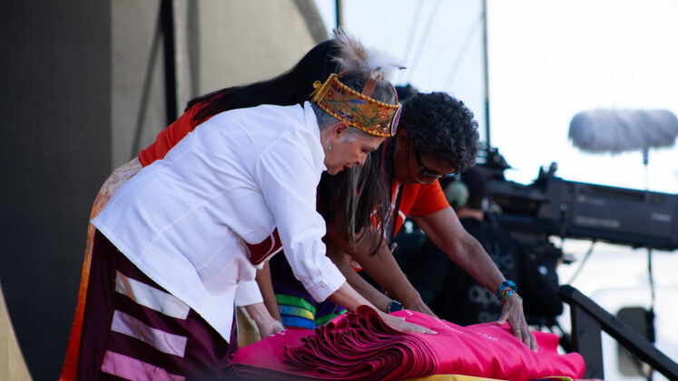 three people fold a banner