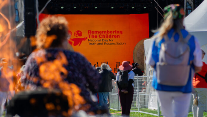 a crowd looks at a stage with a backdrop saying 
