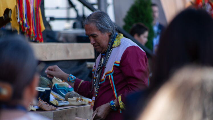 a man wearing a ribbon shirt places shoes on a platform