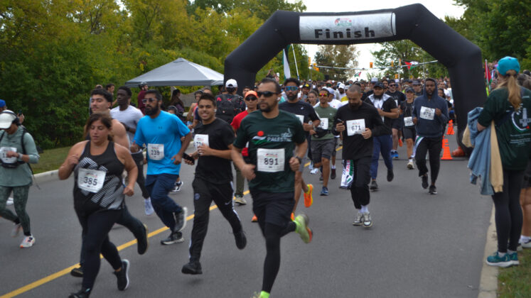 A group runs away from an inflatable race start line.