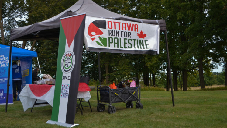 A black tent decorated with a Palestinian flag and a banner saying "Ottawa Run for Palestine."