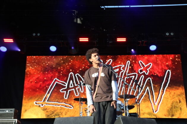 A singer performs on a stage in daylight
