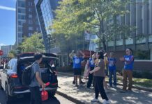 From a new bookstore to Rideau House’s first days, campus comes back to life for new academic year People in blue shirts cheer on person opening up black trunk.