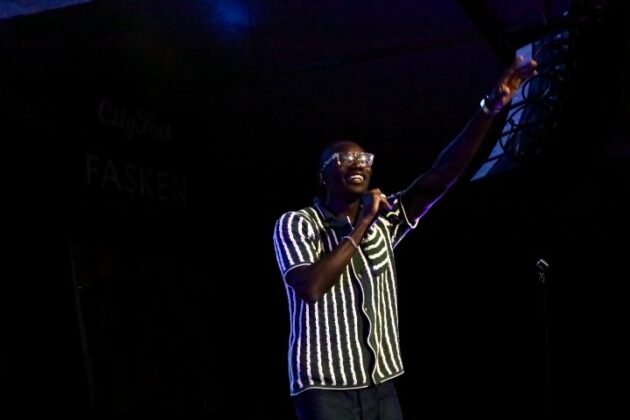 A singer performs with his arms up on stage.