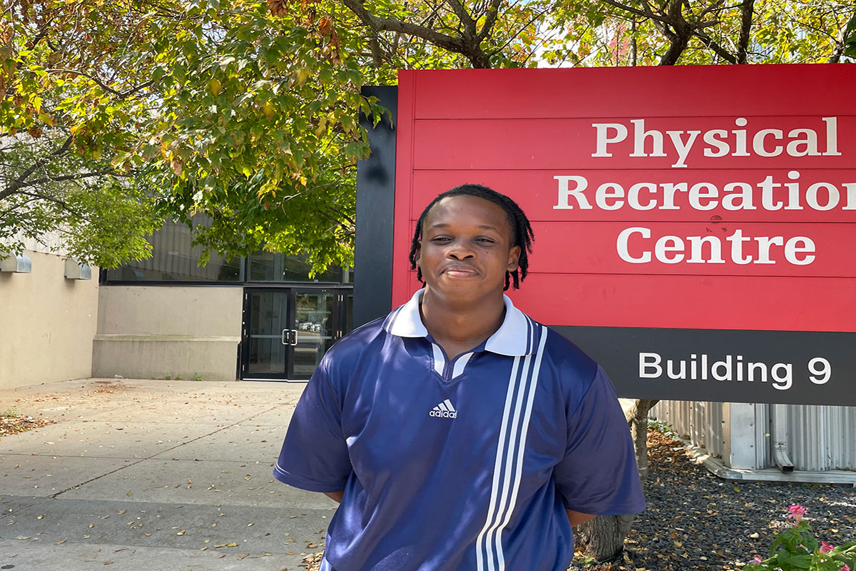 a person stands in front of a carleton sign