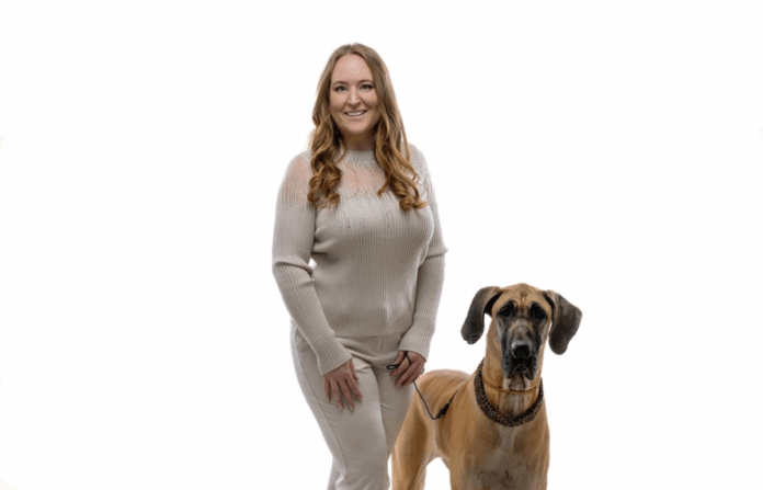 Imagine of Michelle Weger and her dog standing beside eachother in a white background.