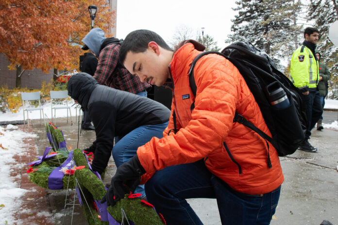 Student puts poppy on wreath.