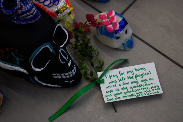 Three skulls on the ground with a note that says: "i pray for my baby who left the physical world a few days ago, as well as my grandgather and great grandparents. May God give strength, who the ones left behind."