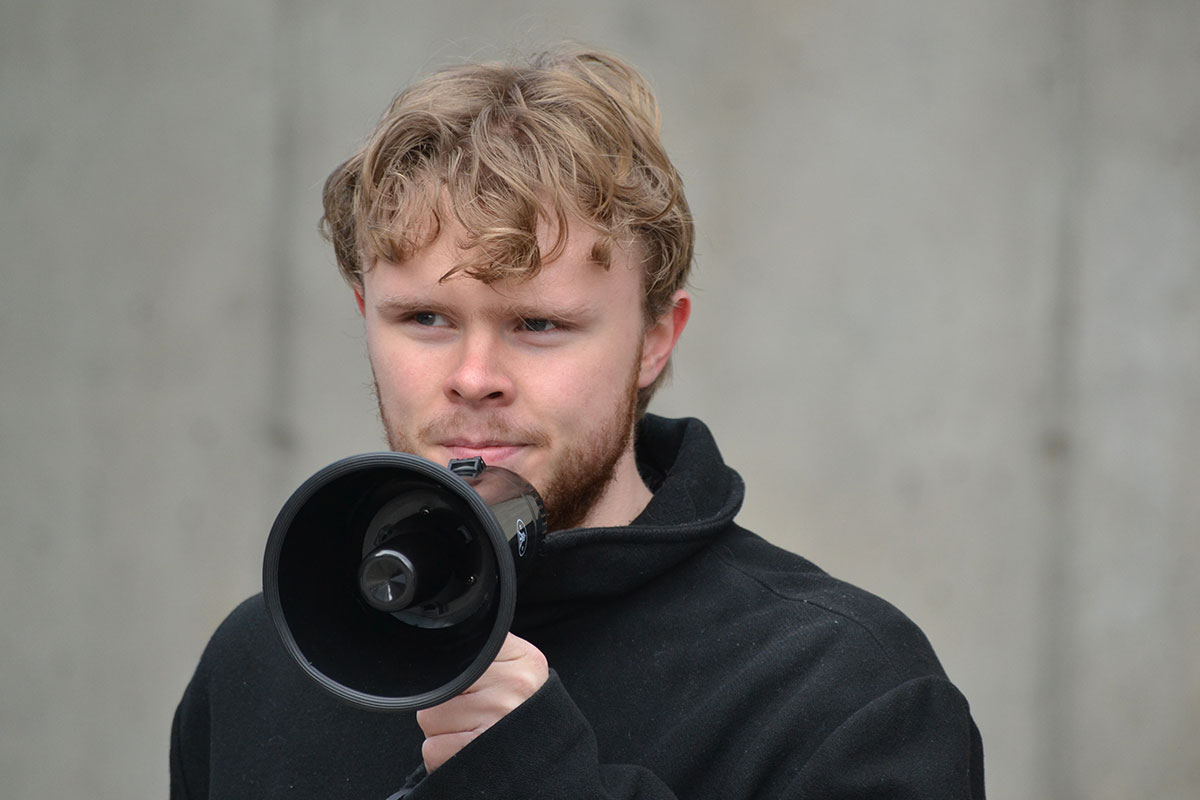 A person holds a megaphone up to his face