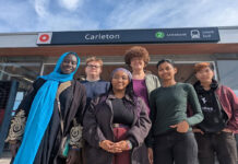 ‘We will be your megaphone’: Carleton advocates talk Ottawa transit accessibility Six people stand in front of a sign with a red circle O-Train logo on it, the word "Carleton," and the number 2 with the words, "Limebank South."