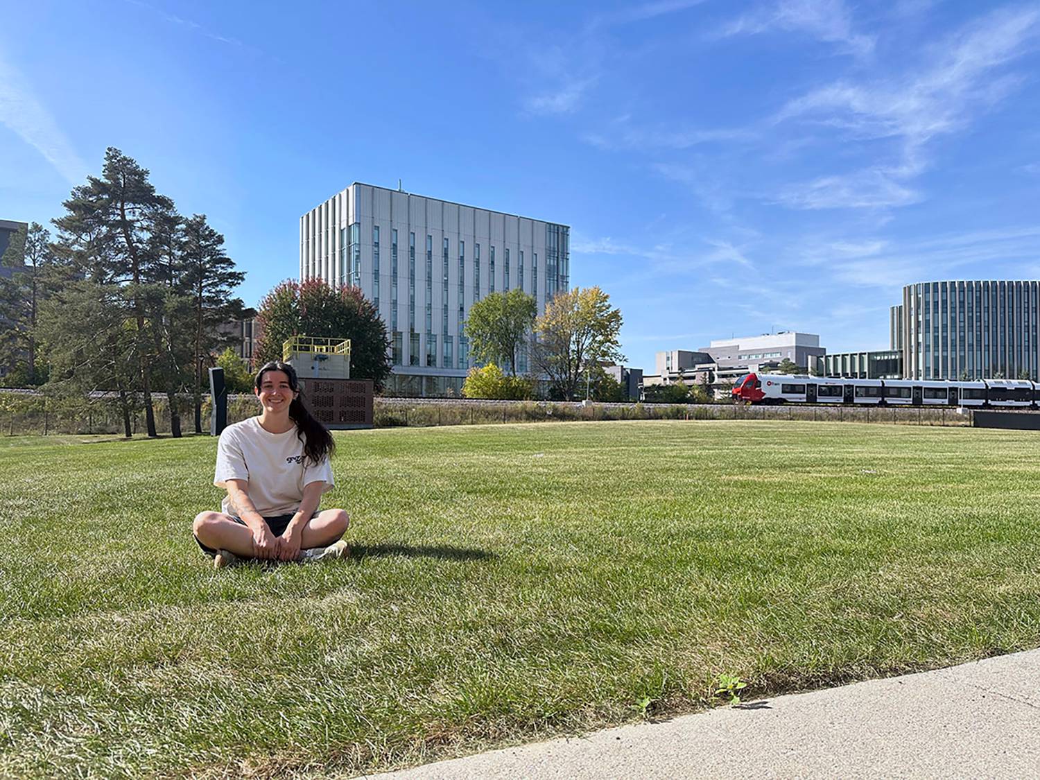 A woman sitting in open empty grass field.