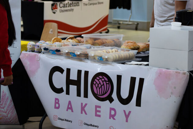 A table with a banner that says "Chiqui Bakery" with cookies, cupcakes and baked goods on top
