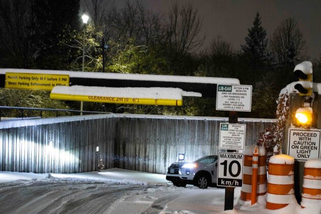 Car drives up a ramp from a underground parking garage during a snowstorm.