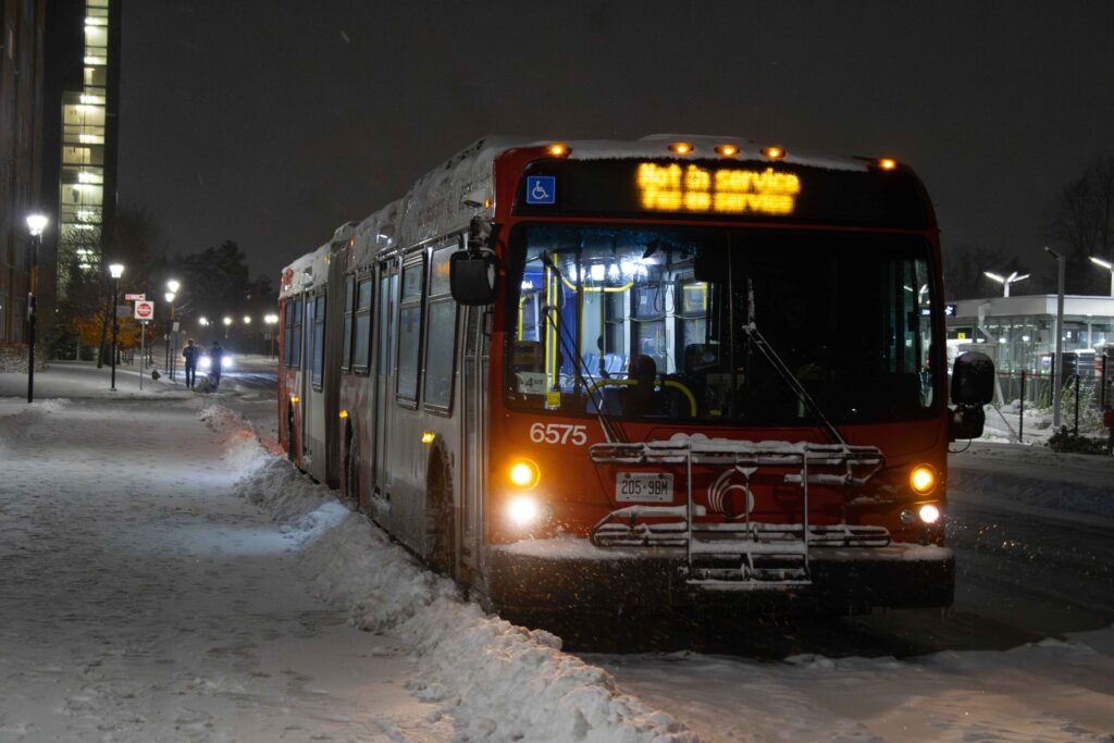 OC Tranpso bus is parked at Carleton during a snowstorm.