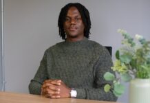 Q&A: CUSA president Sean Joe-Ezigbo on finances, parking and transparency, halfway into his term man wearing green shirt sits at desk in CUSA president office.