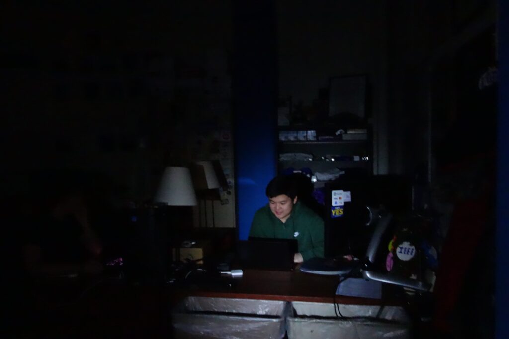 A man sitting in darkness at a desk.