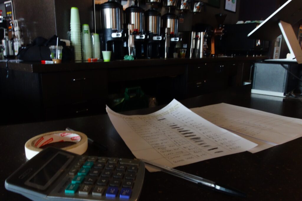 A calculator and papers strewn across a table in a cafe.