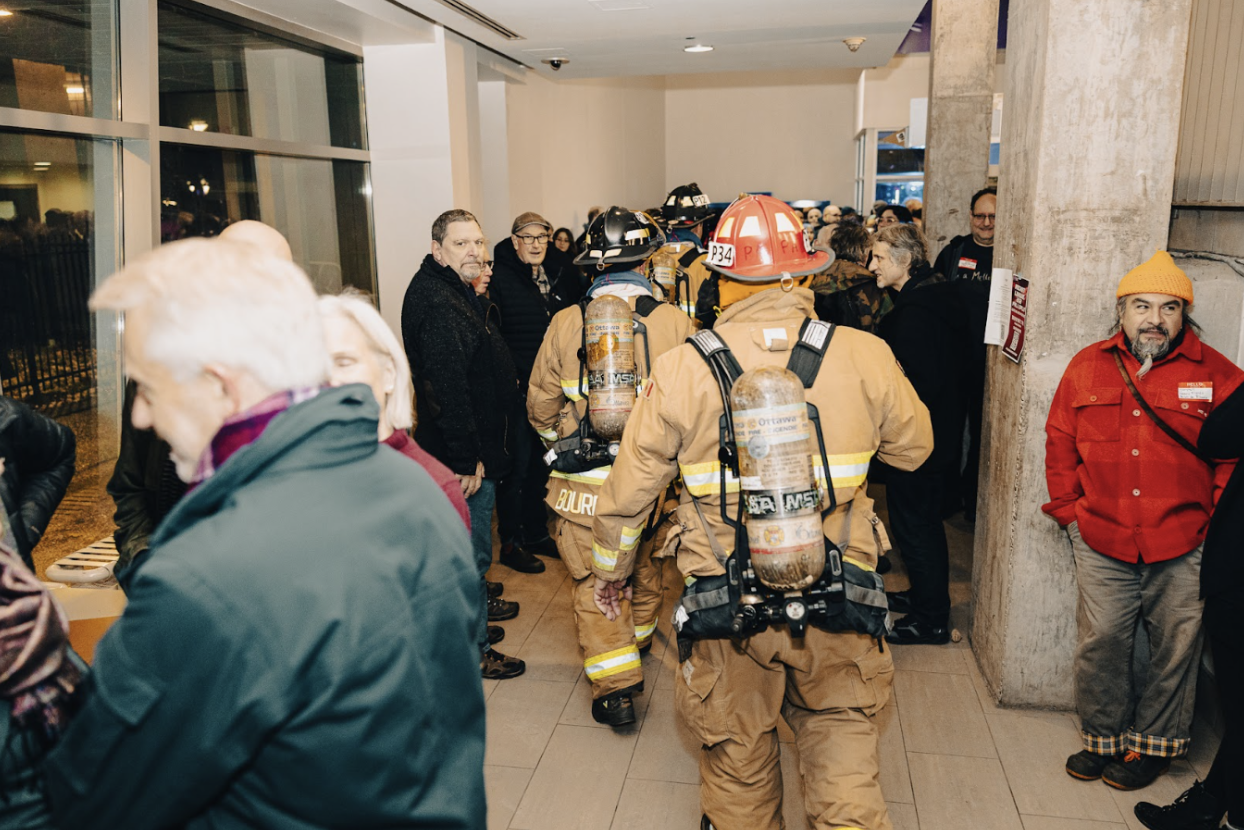 Firefighters leaving a building and a white haired man to the left