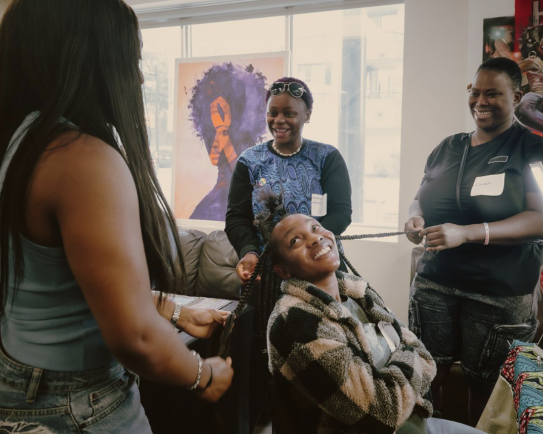 Four Black women interacting while doing hair