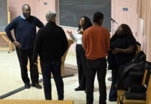 Carleton research findings reveal ways journalists can better report on Black communities Five people - three facing to the camera and two facing away - are engaging in a seemingly vivacious conversation in a university classroom. They are all standing.